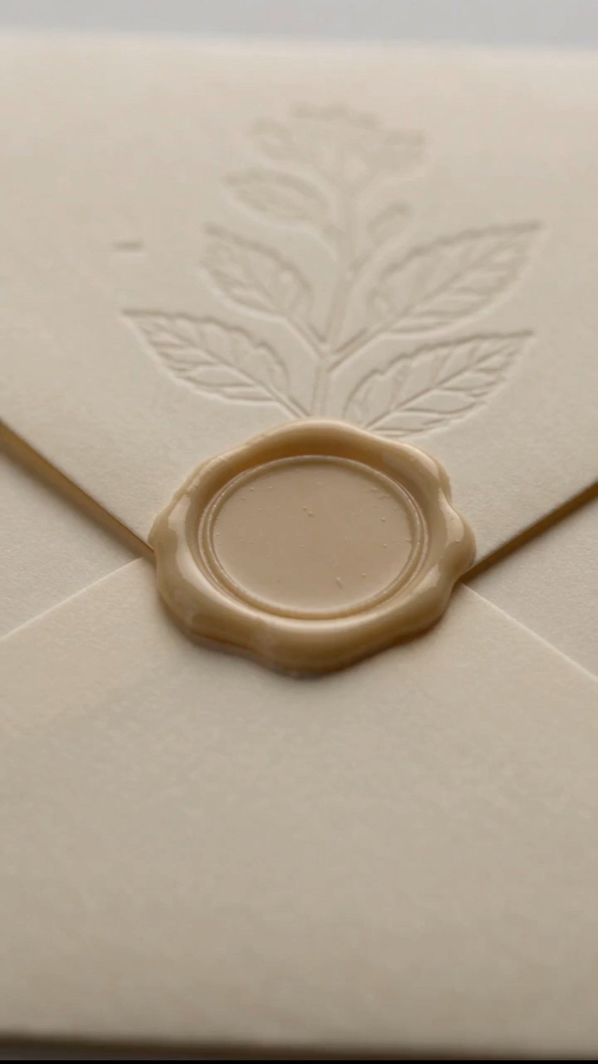 A sealed cream envelope with a gold wax seal